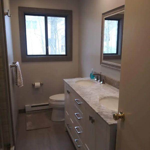 A bathroom with two sinks, a toilet, and a mirror