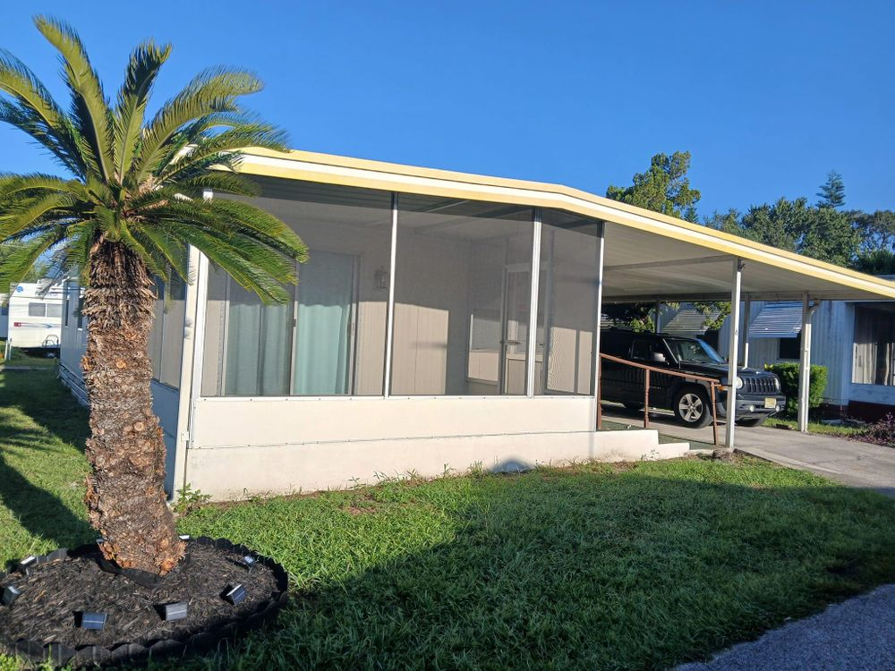A mobile home with a screened in porch and a palm tree in front of it