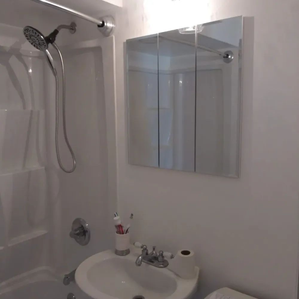 A bathroom with a sink a toilet a shower and a mirror