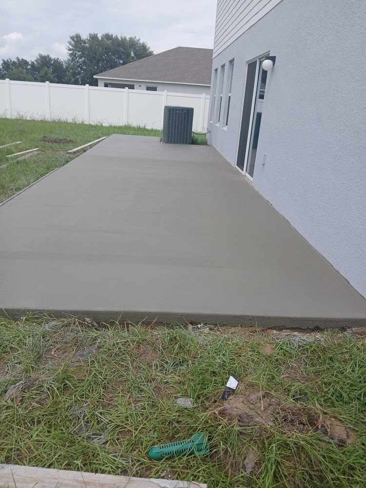 A concrete patio is being built in the backyard of a house