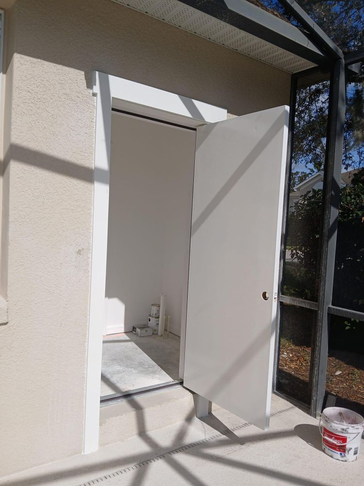 A white door is open to a room on the side of a house