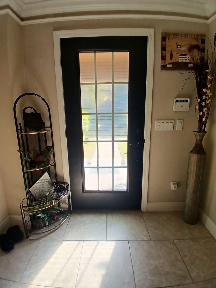 A hallway with a black door and a vase on the floor