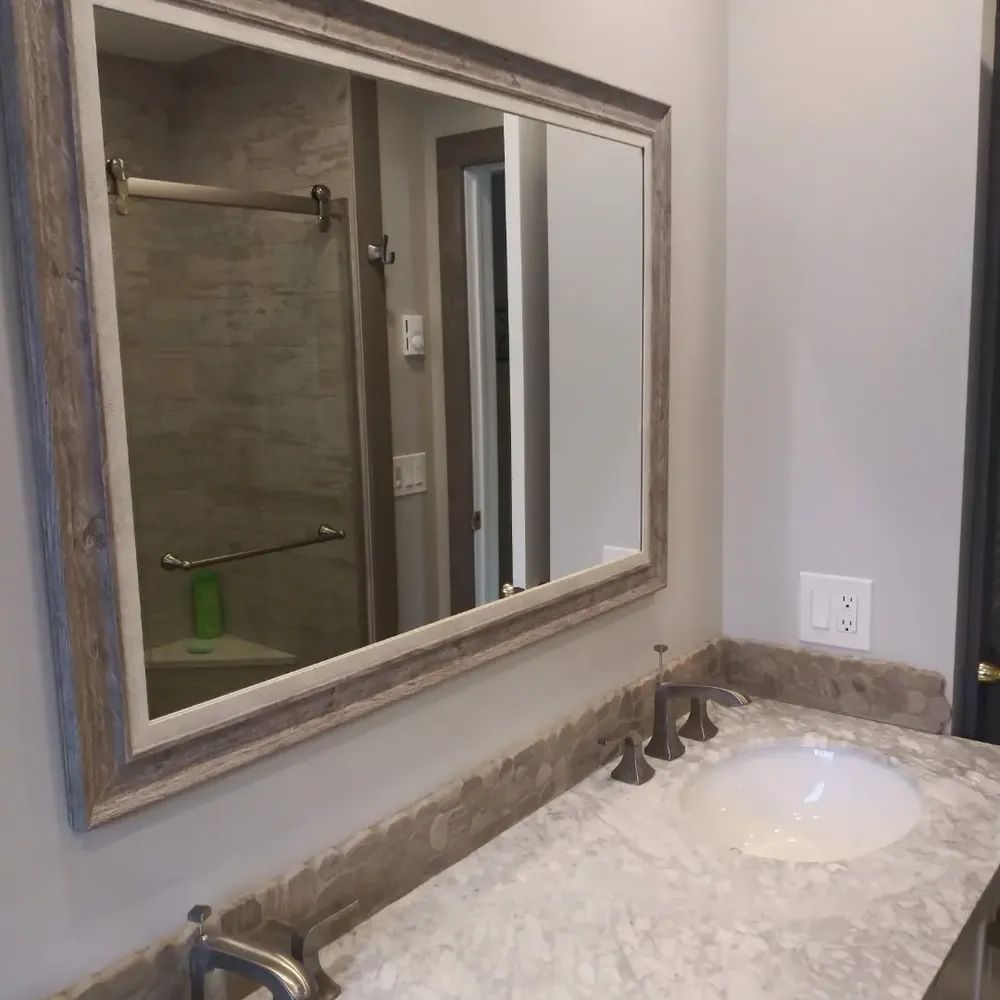A bathroom with a sink, mirror and shower
