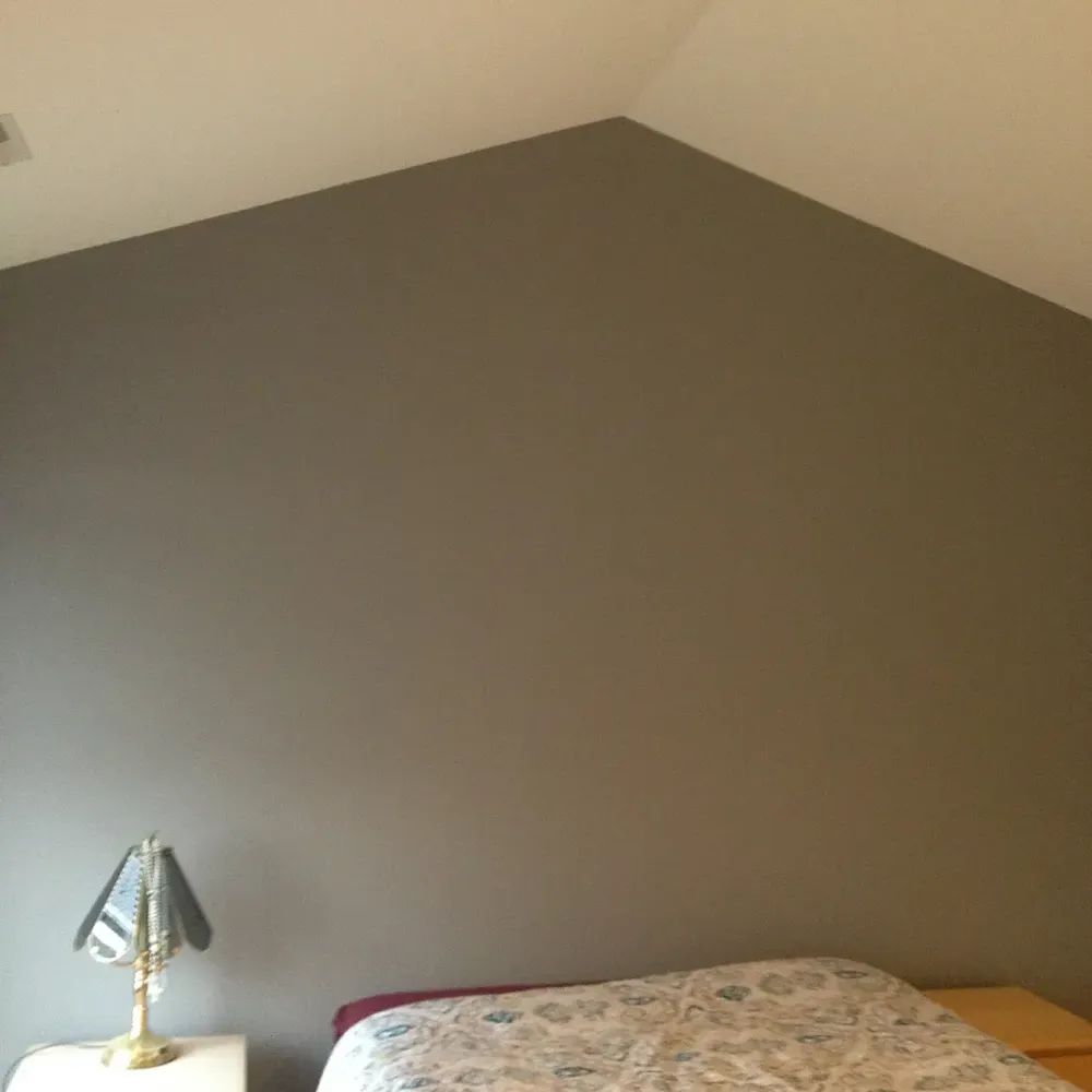 A bedroom with a bed, nightstand, lamp and gray walls