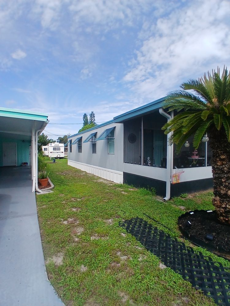 A mobile home with a screened in porch and a palm tree in front of it