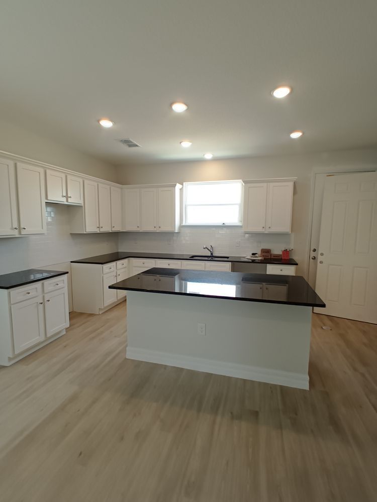 An empty kitchen with white cabinets and black counter tops