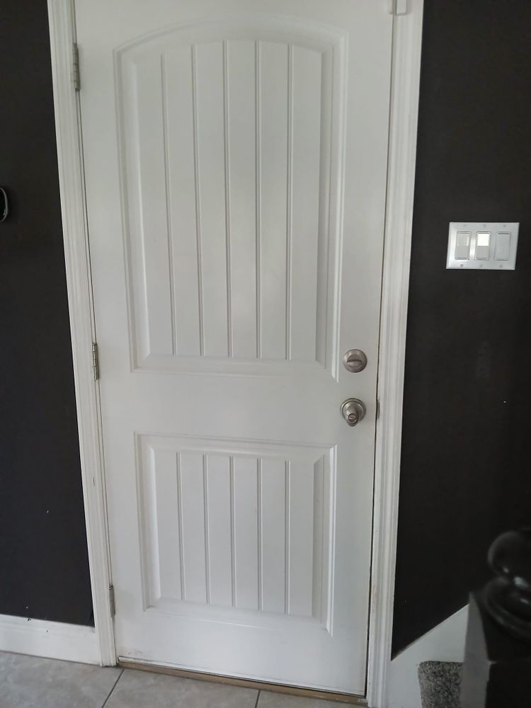 A white door is sitting in a room next to a black wall.