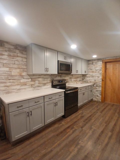 A kitchen with white cabinets, a stove and a microwave