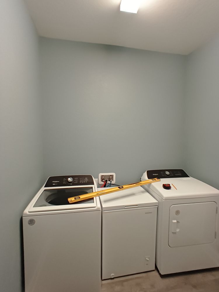 A laundry room with a washer and dryer and a measuring tape
