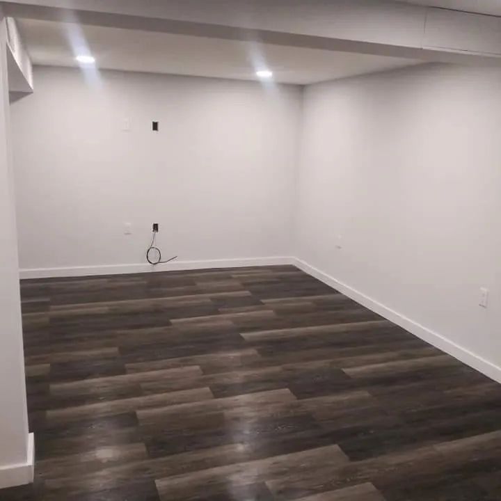An empty room with a wooden floor and white walls