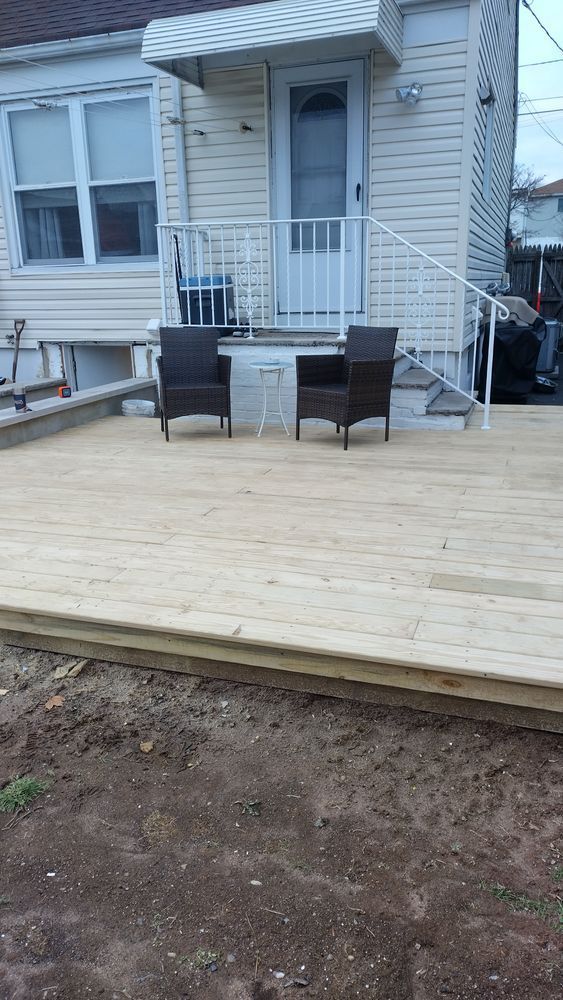 A wooden deck with chairs and a table in front of a house