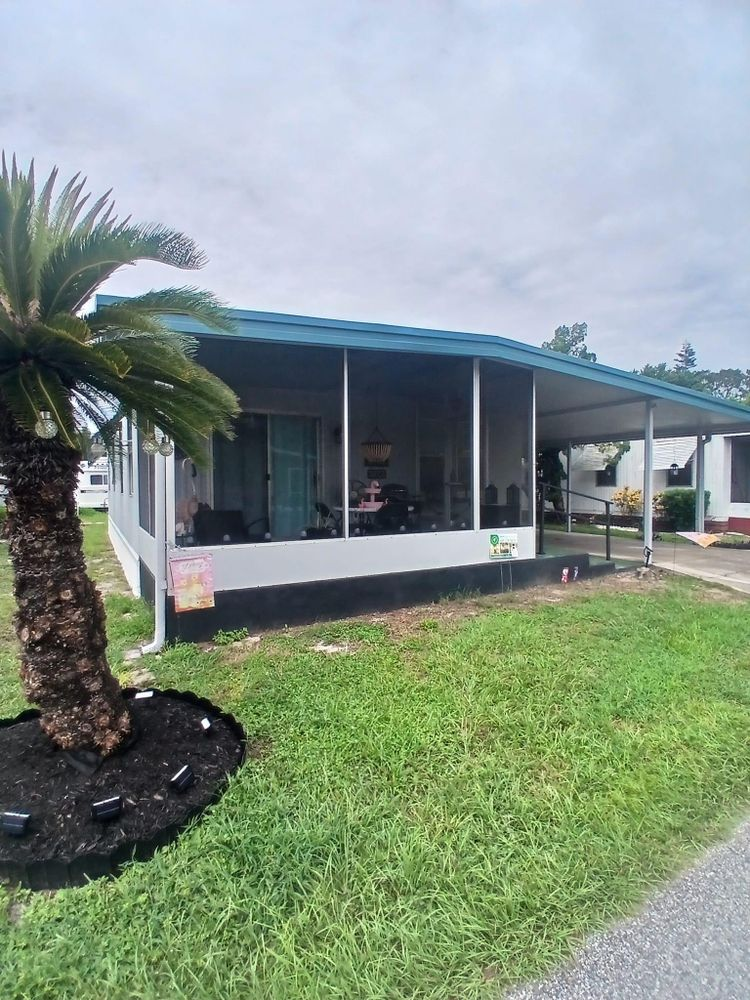 A mobile home with a screened in porch and a palm tree in front of it