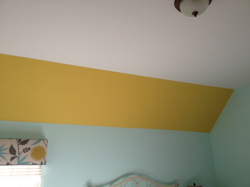 A bedroom with a yellow and white ceiling