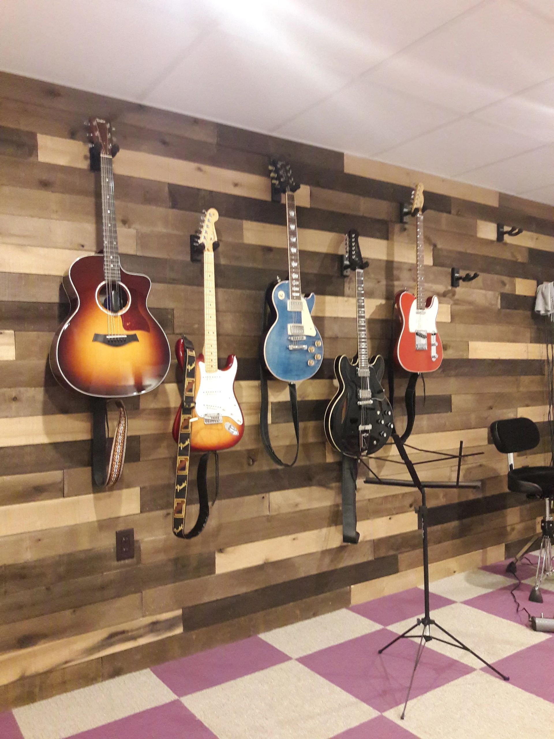 Several guitars are hanging on a wooden wall