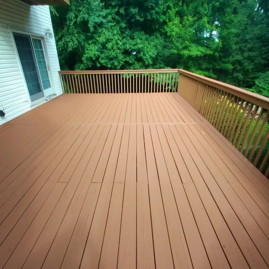 A wooden deck with a railing and trees in the background