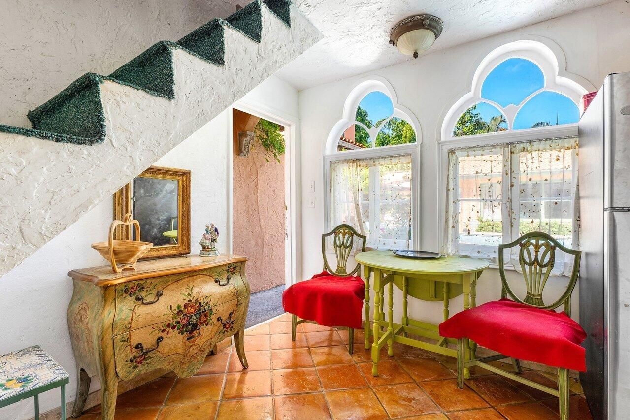 A living room with a dresser , table , chairs and stairs.