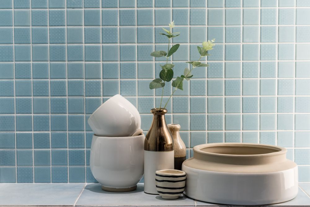 A Vase With A Plant In It Is Sitting On A Counter Next To Bowls And Vases — Tile Power Dubbo In Dubbo, NSW