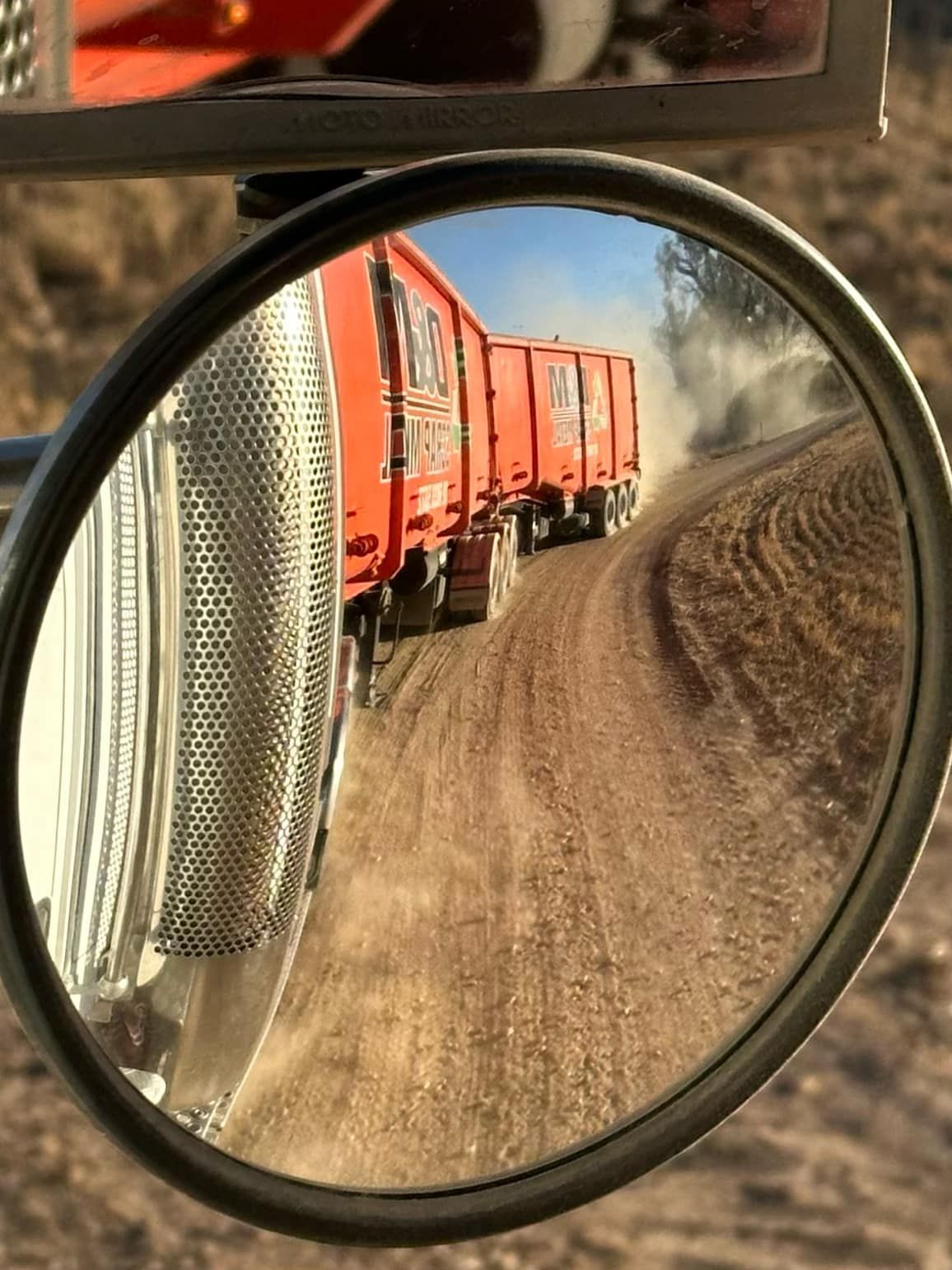 A reflection of the back of the orange truck trailers.