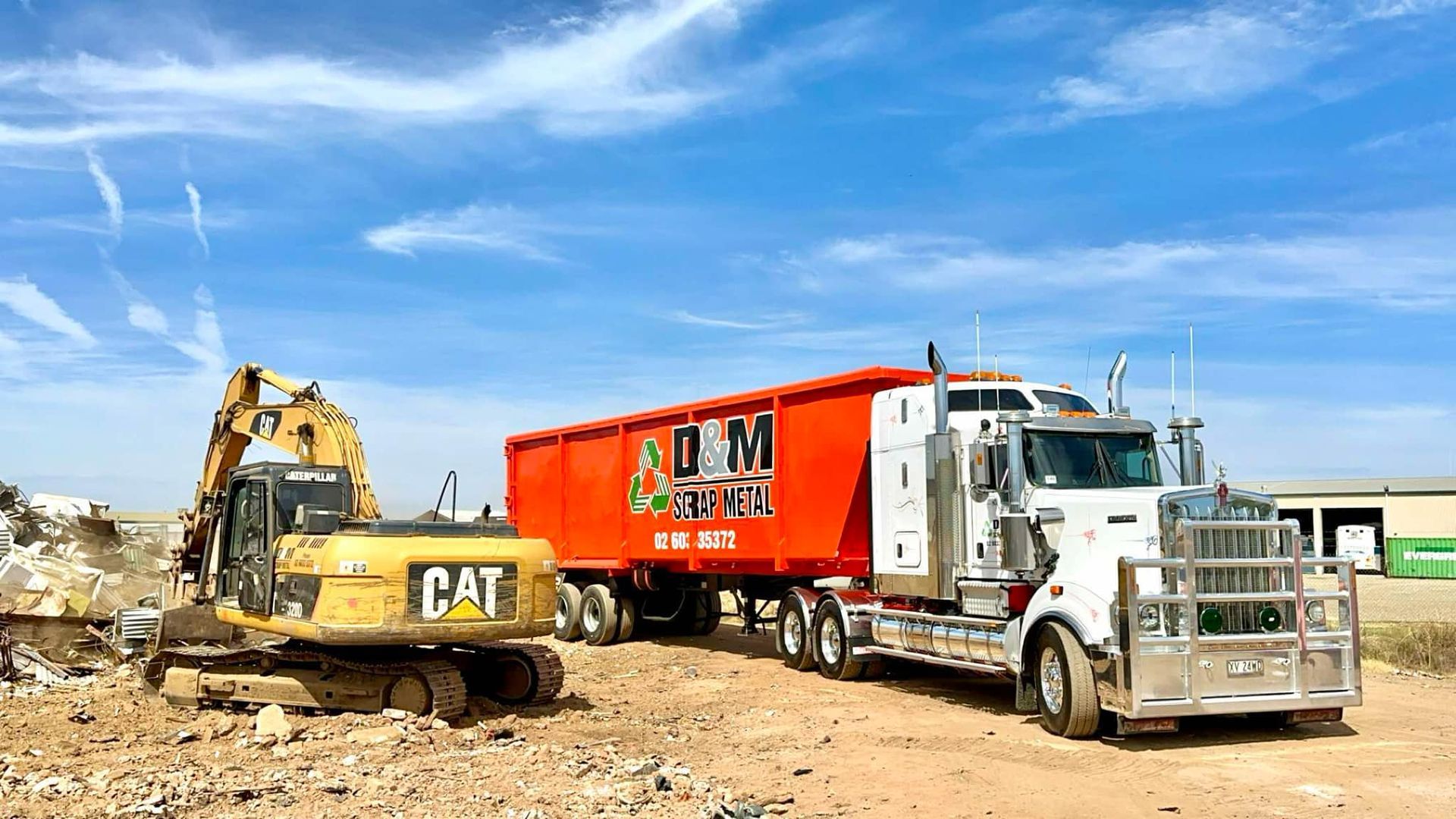 A yellow excavator preparing to load onto a orange truck.