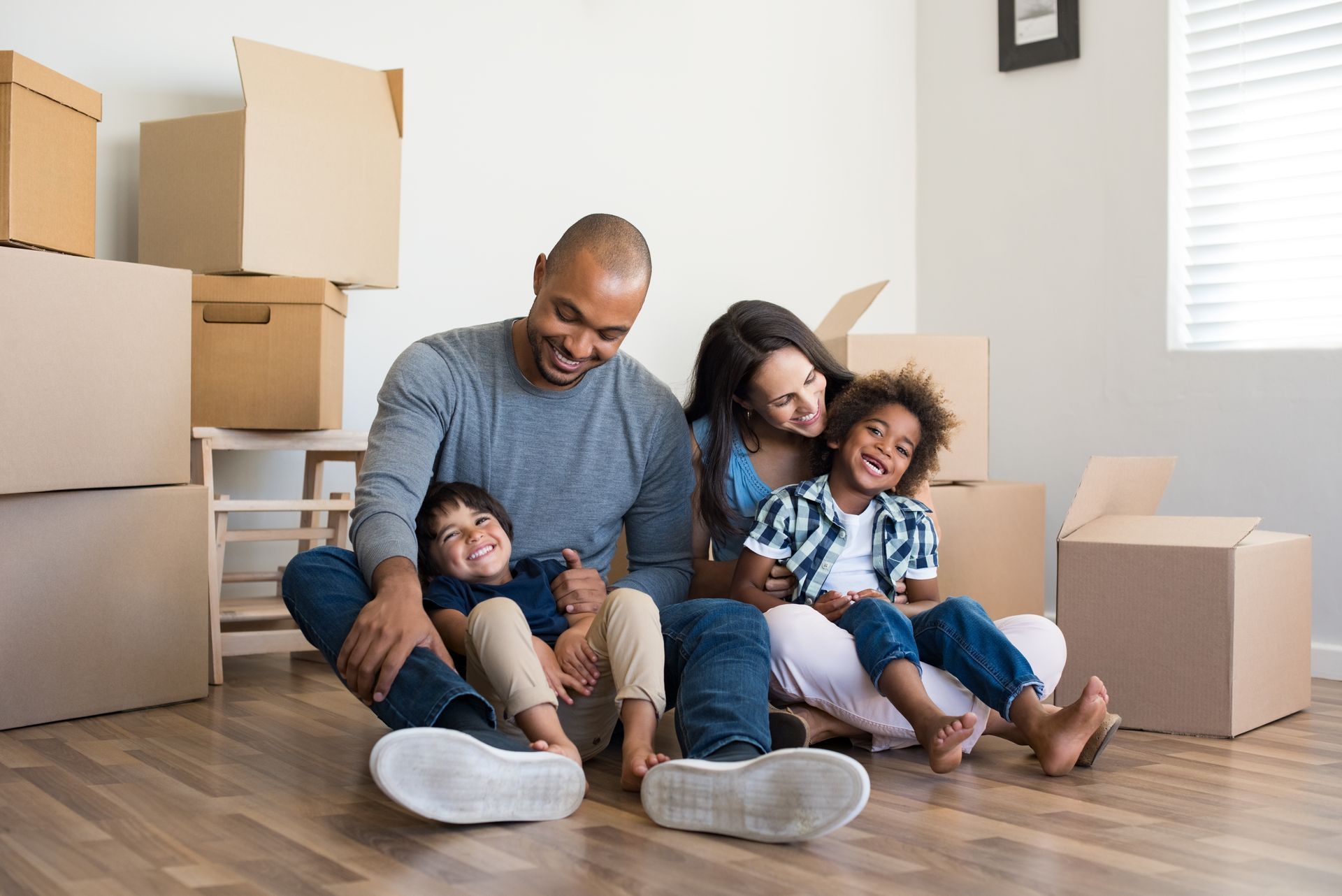 Image of a family consisting of a brown man, white woman, and two brown boys sitting on the floor.