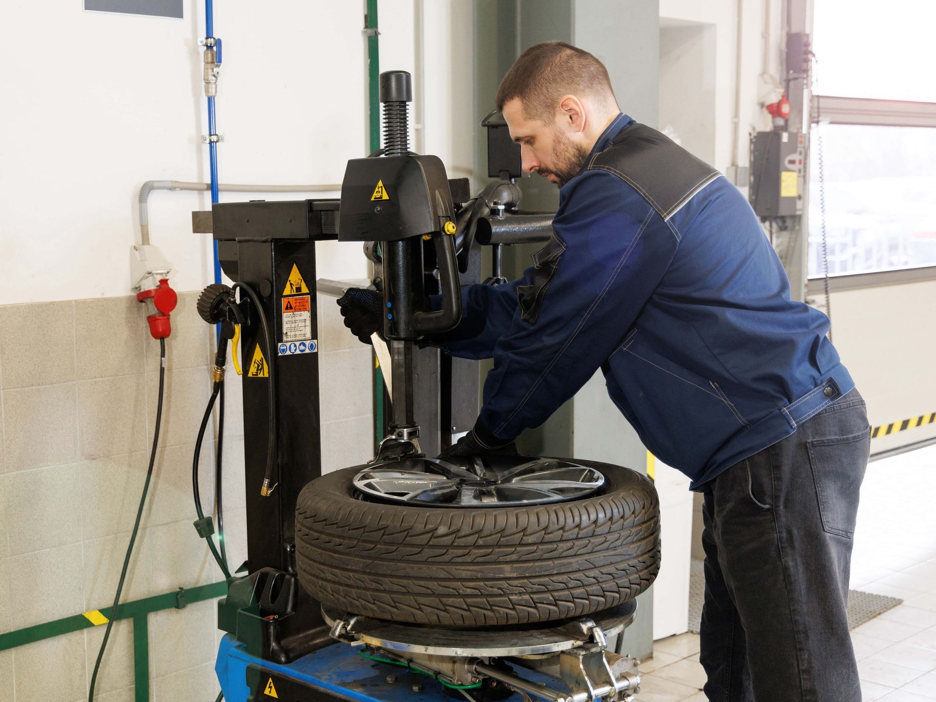 Mechanic using a tire machine to change a tire in a garage.