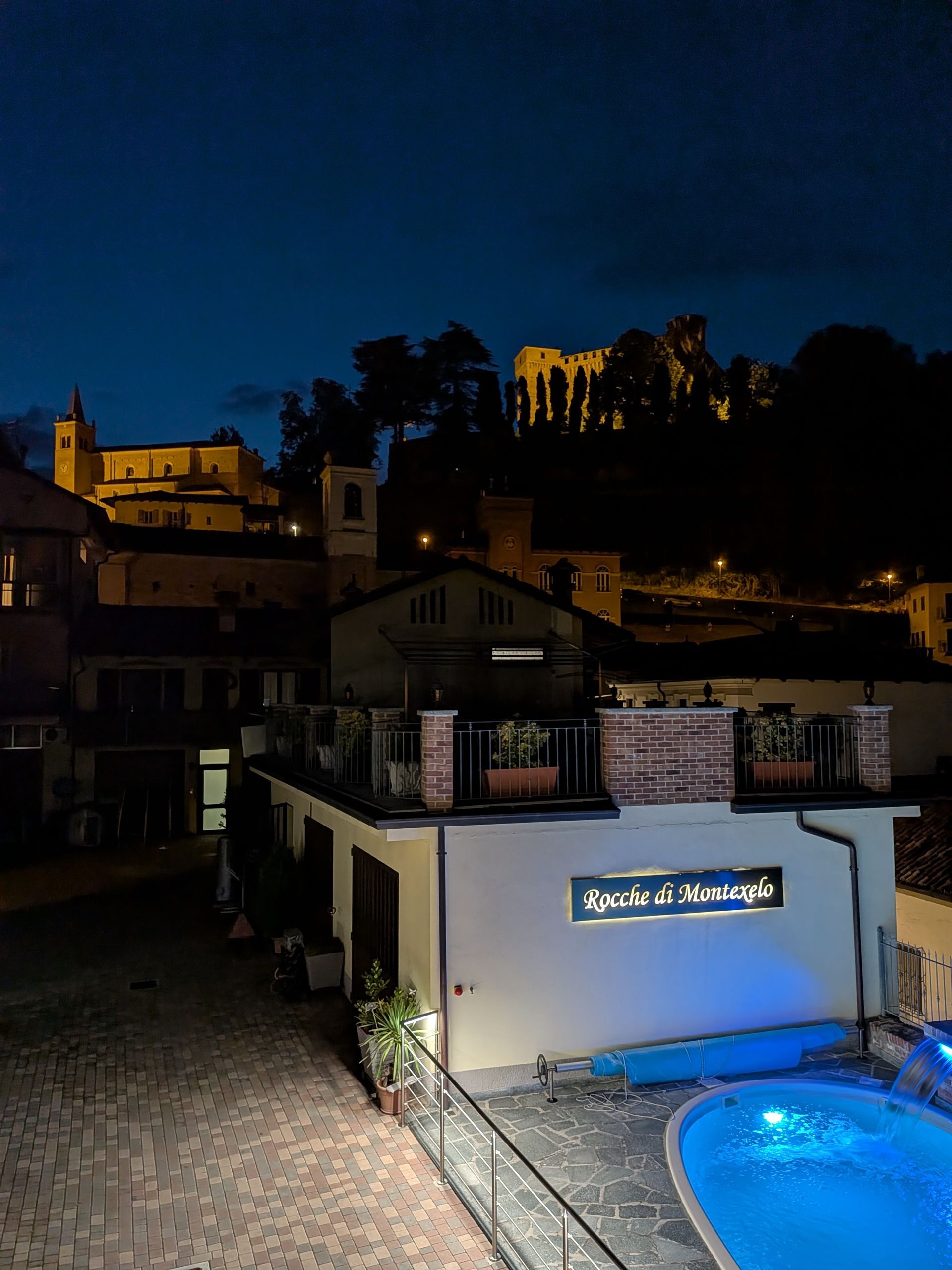 Panoramic terrace view of Greenpool at Rocche di Montexelo and illuminated castle at night during summer