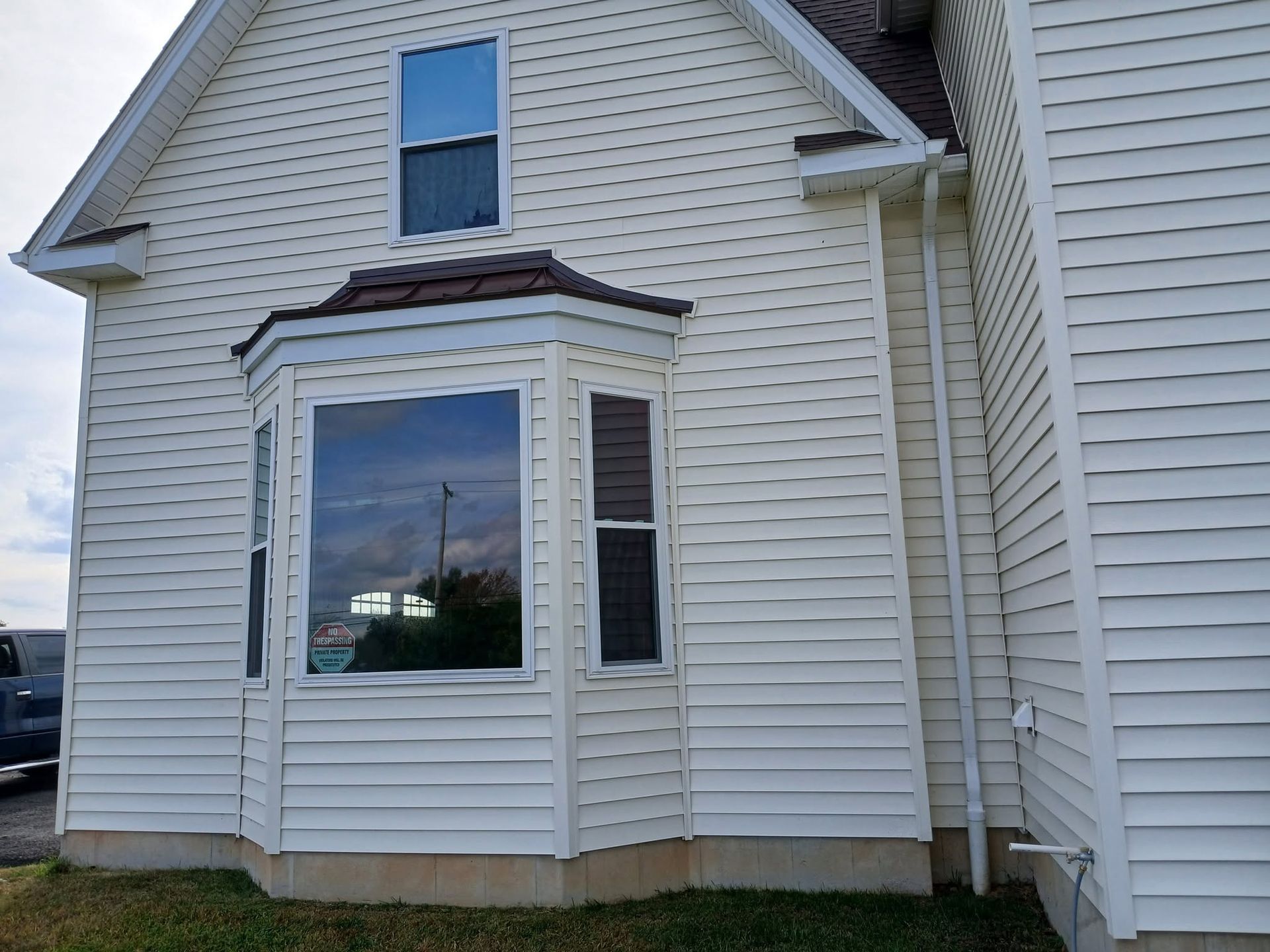Exterior of a white house with a large bay window and gray trim