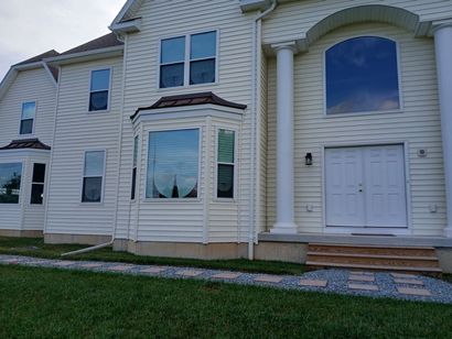 Front view of a beige townhouse with a white double door, large windows, and a small front lawn.