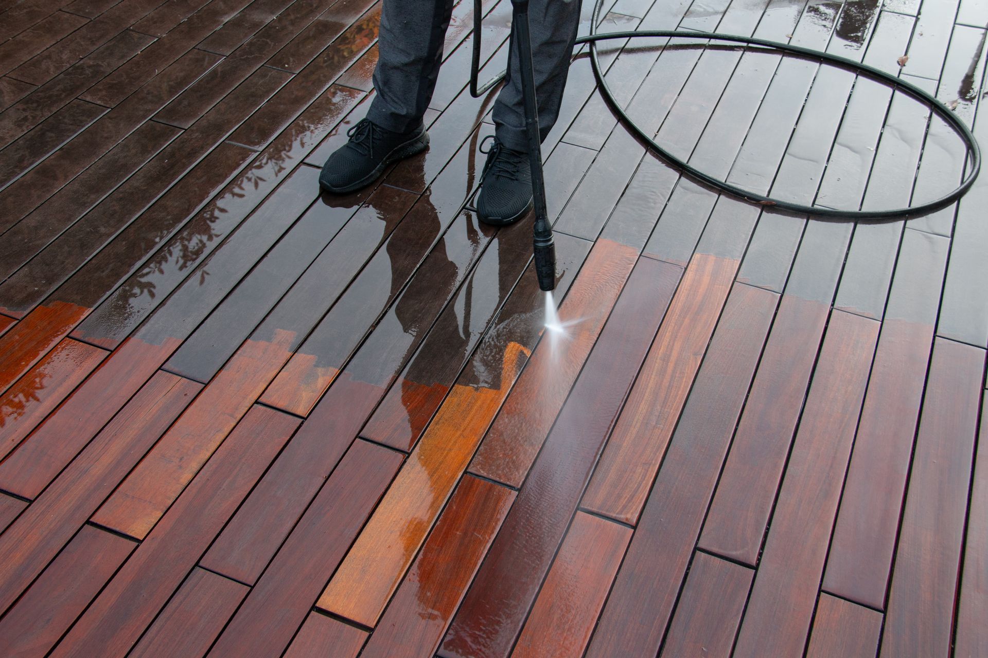 Person standing on wet wooden deck with a large circular hoop nearby
