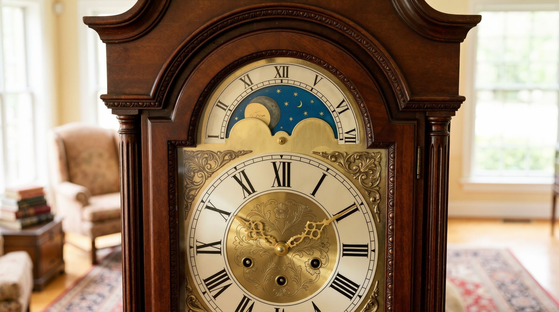 Antique wooden grandfather clock with a brass face and blue moonphase dial in a bright living room.