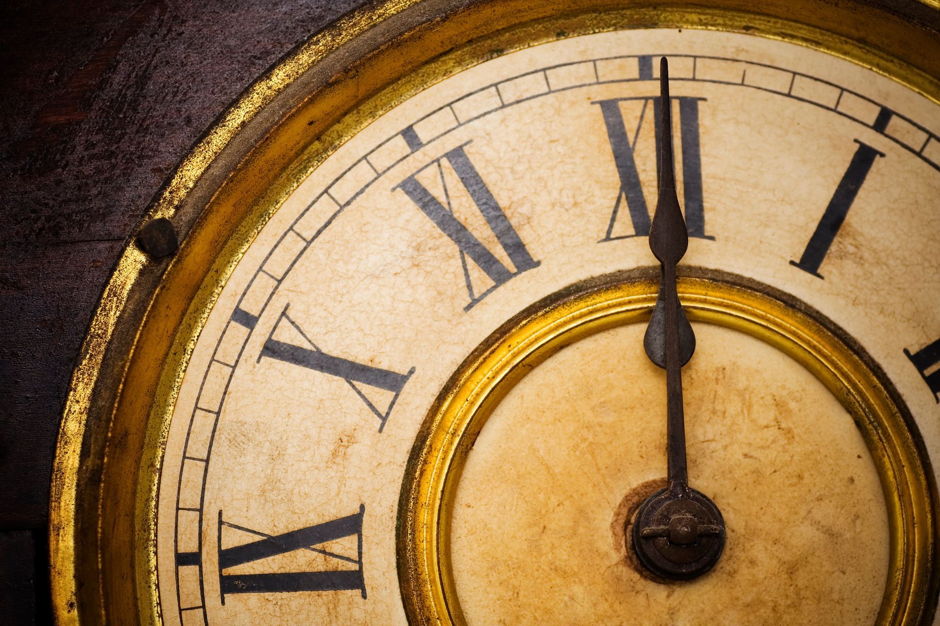 Close-up of antique grandfather clock, showcasing gold gilding and roman numerals face.