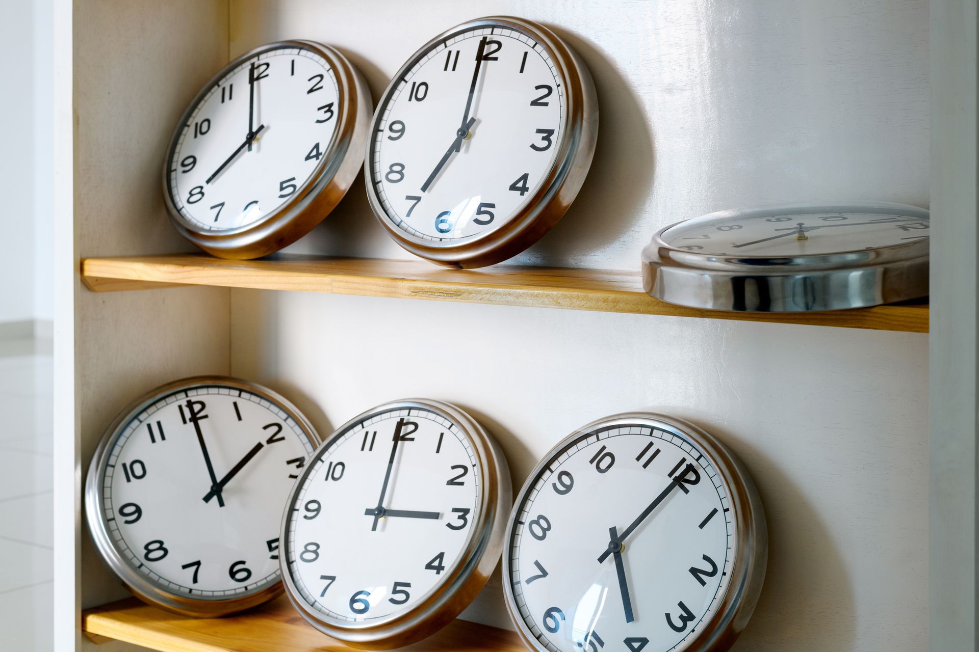 A bunch of clocks are sitting on a wooden shelf