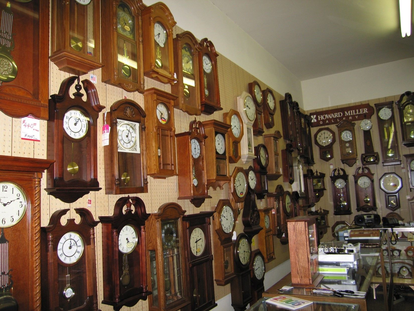 Wall lined with a variety of antique wooden clocks in a shop setting.