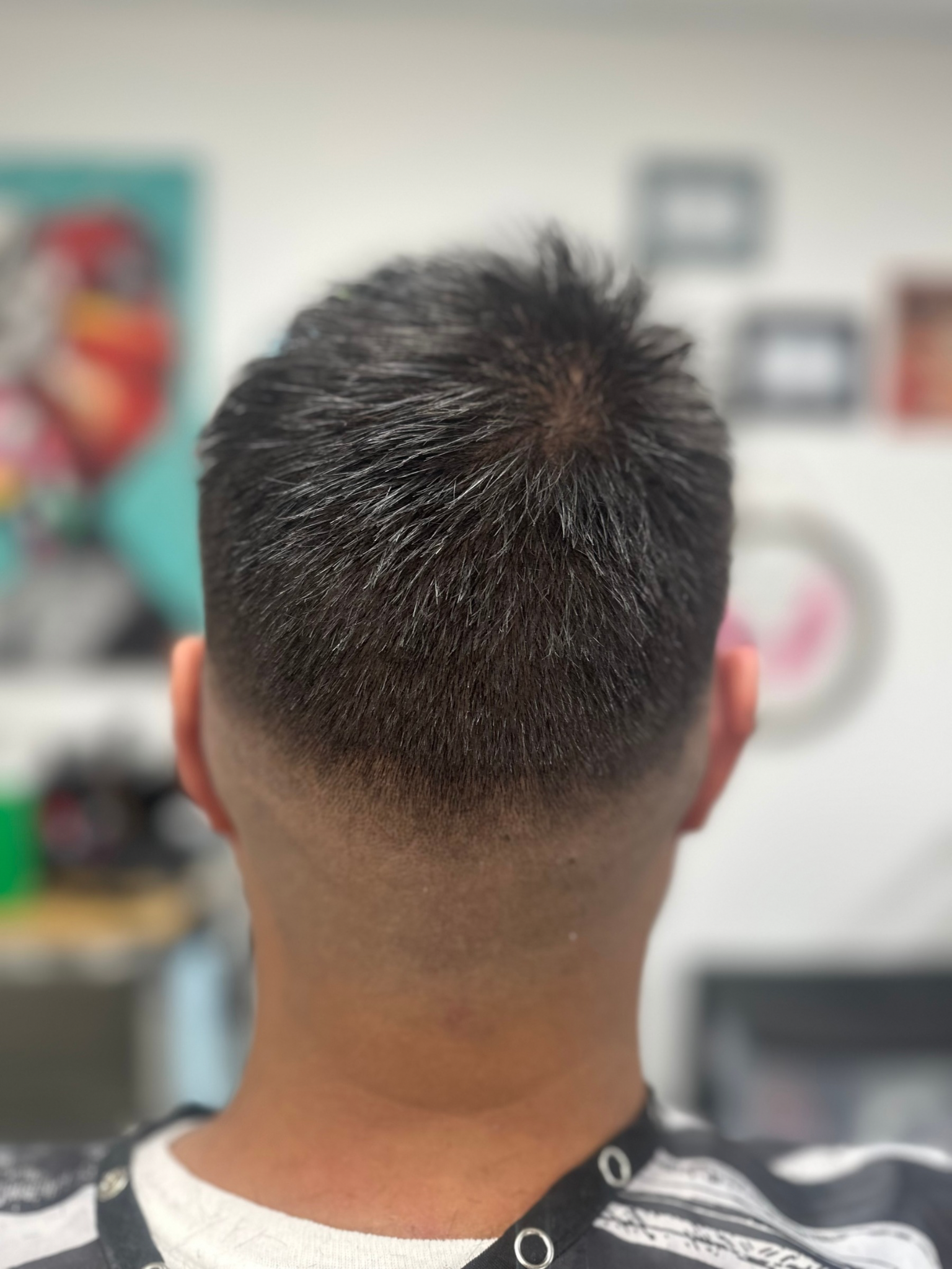 Close-up of the back of a person's head, showing a fade haircut. The hair is dark on top, fading to a skin tone.