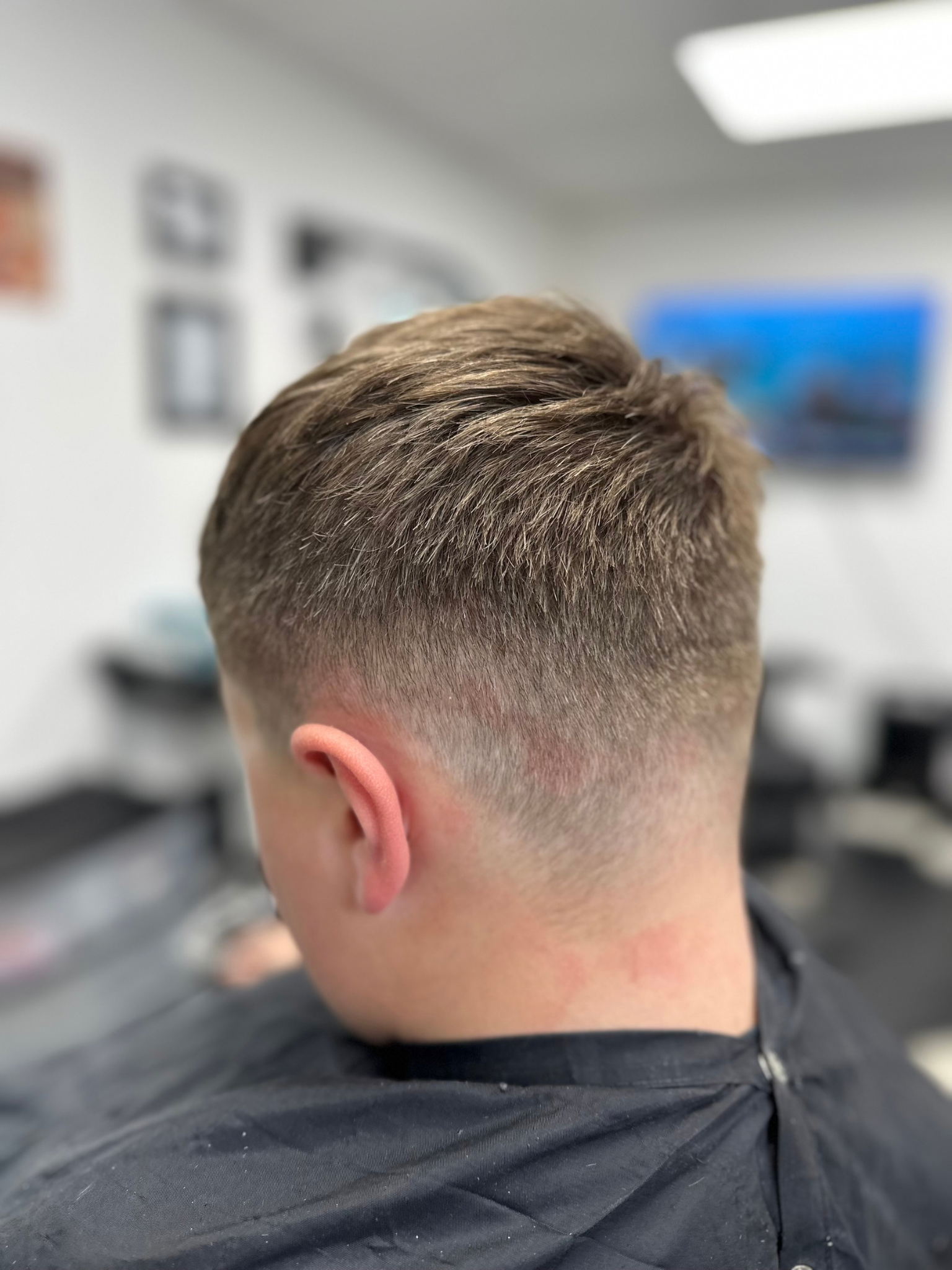 Close-up of a person's head after a haircut, showcasing a skin fade with short hair on top.