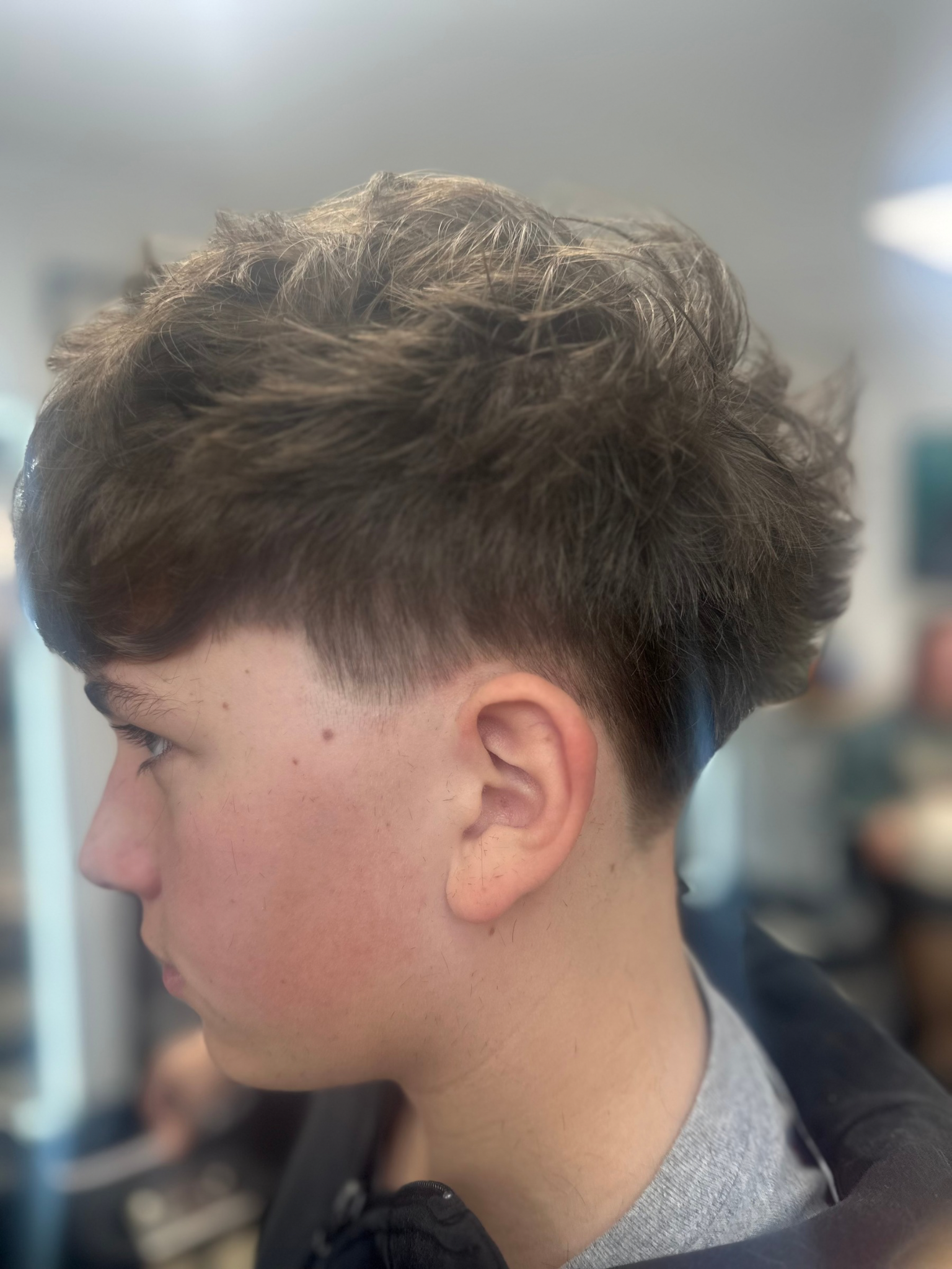 Boy with dark hair; haircut with faded sides and textured top.