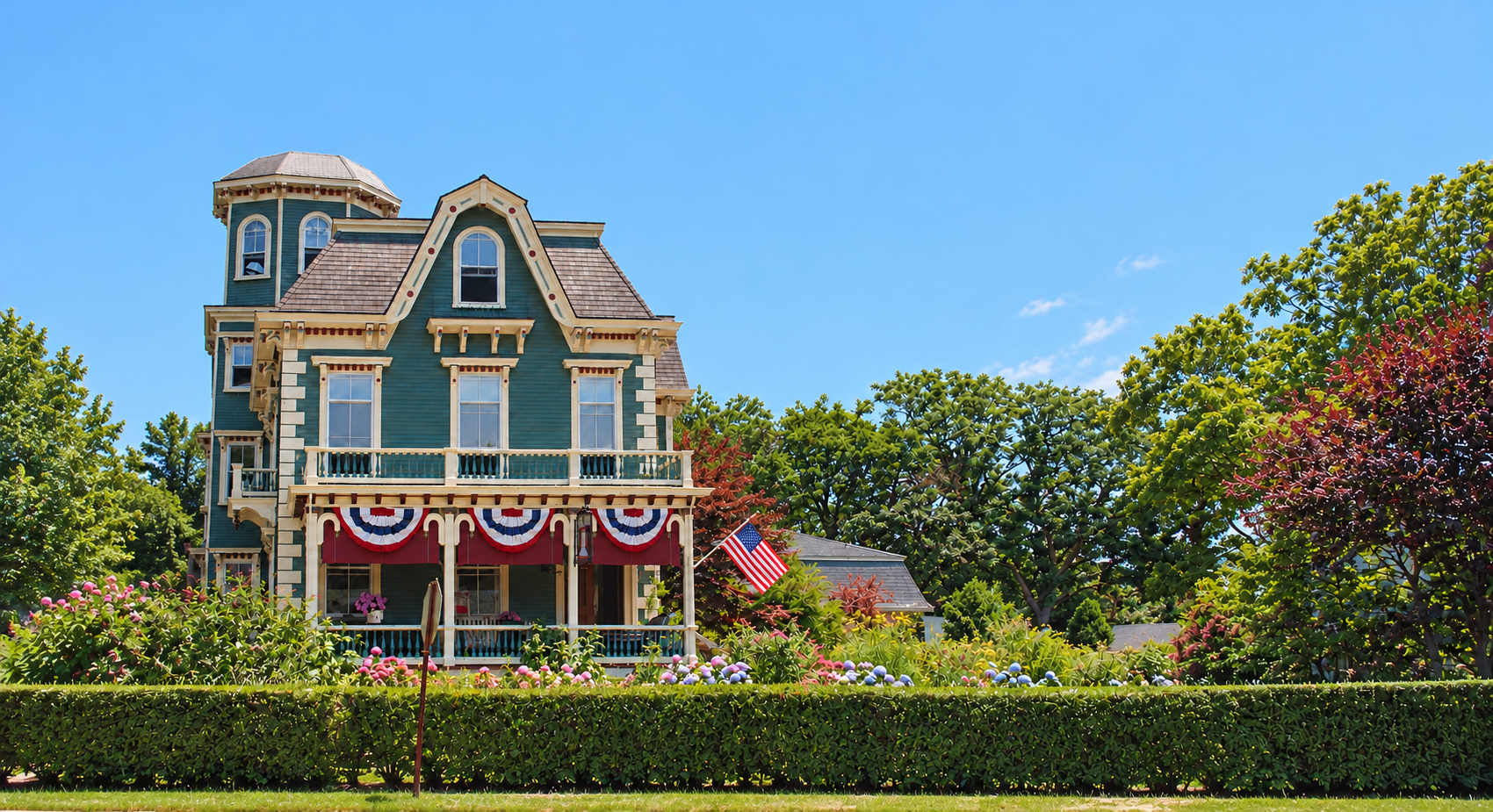 Victorian house with blue siding, white trim, and a sunlit garden in front