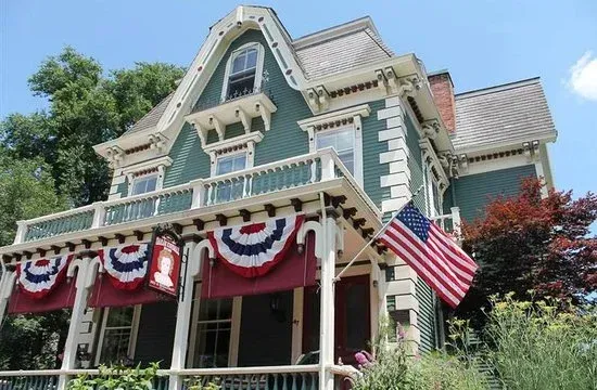 Victorian house with patriotic red, white, and blue bunting and an American flag on the porch