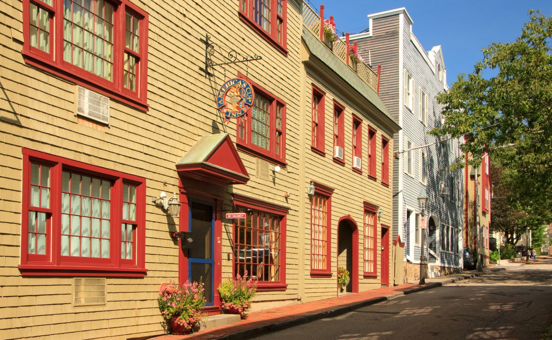 Colorful historic rowhouses with red-trimmed windows along a sunlit street.