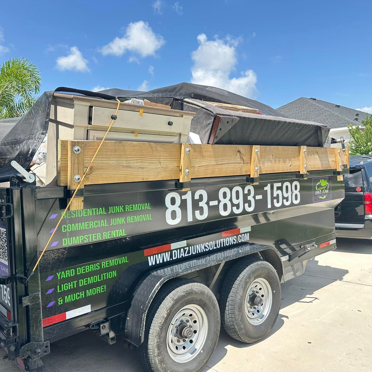 Dumpster trailer loaded with furniture; Diaz Junk Solutions logo and phone number visible.