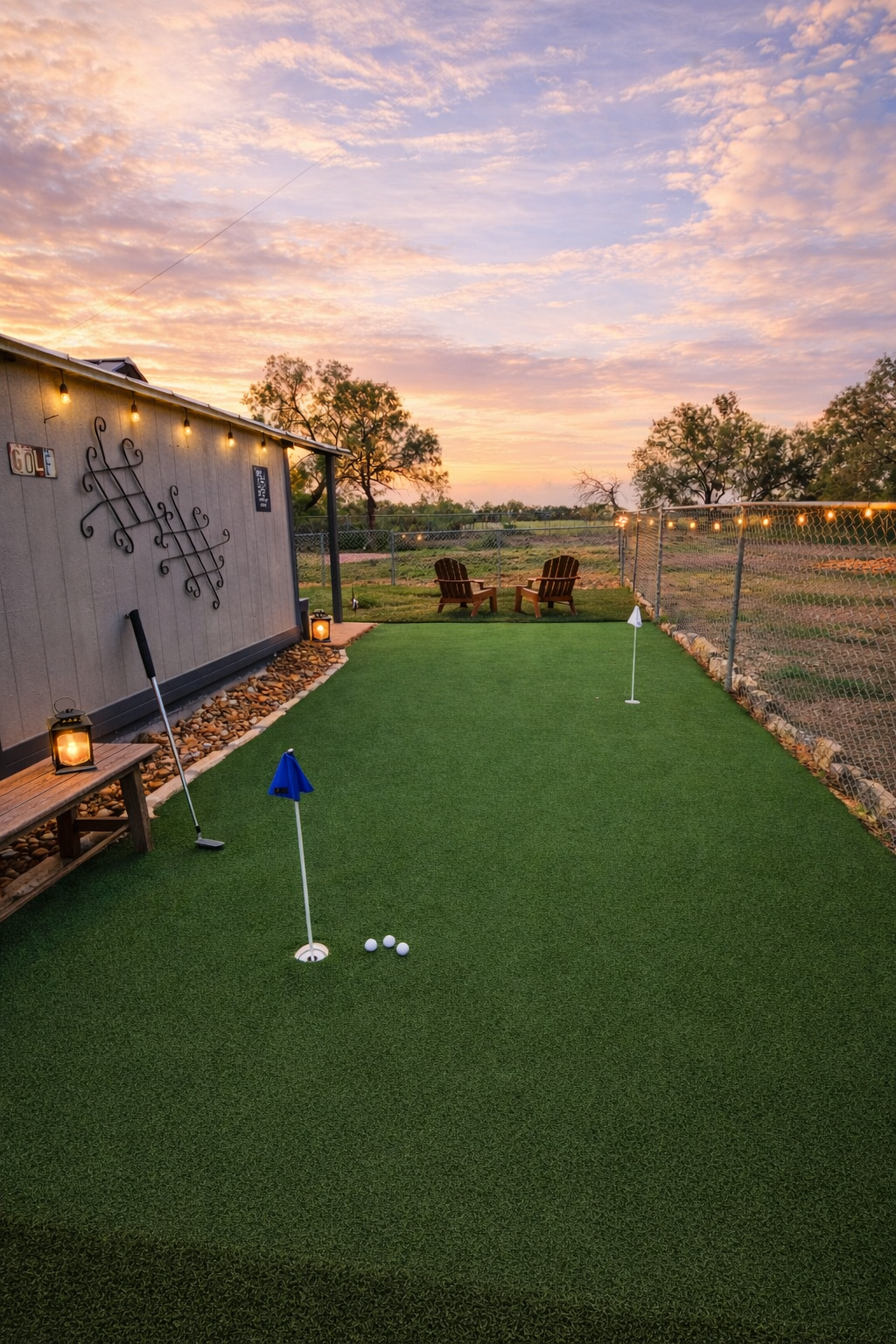 Mini golf putting green at sunset with a red flag, string lights, and a painted wall mural.