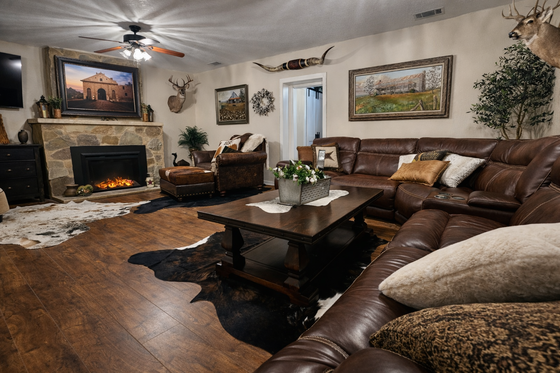 Cozy living room with leather sofas, fireplace, coffee table, and wall art in warm tones