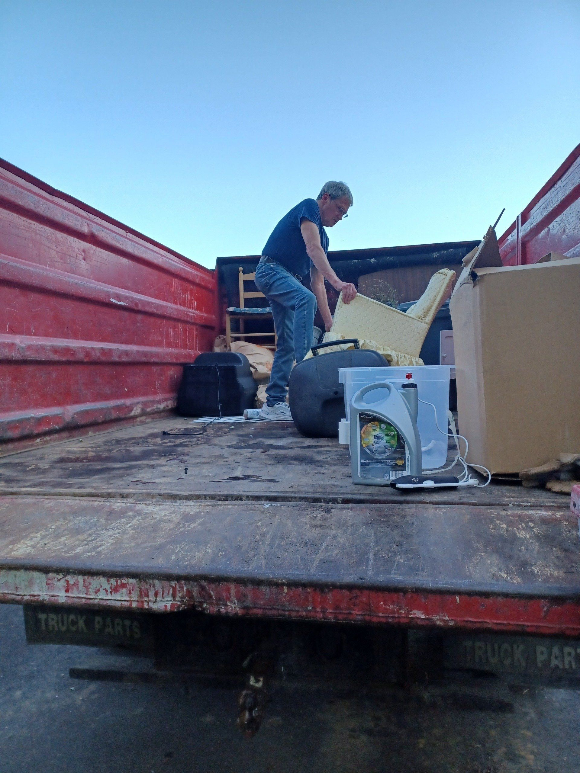 Man loading cardboard onto a truck bed with red side panels and boxes nearby