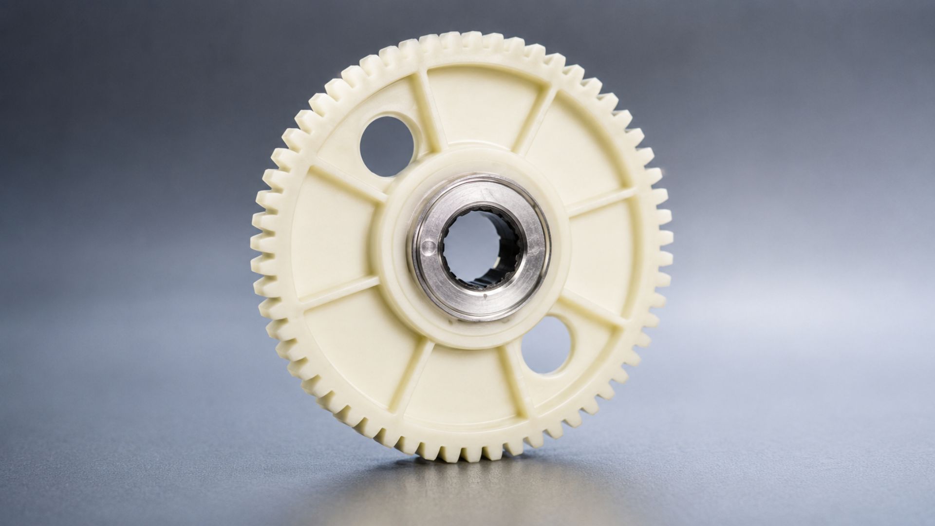White plastic gear with a metal center on a gray background