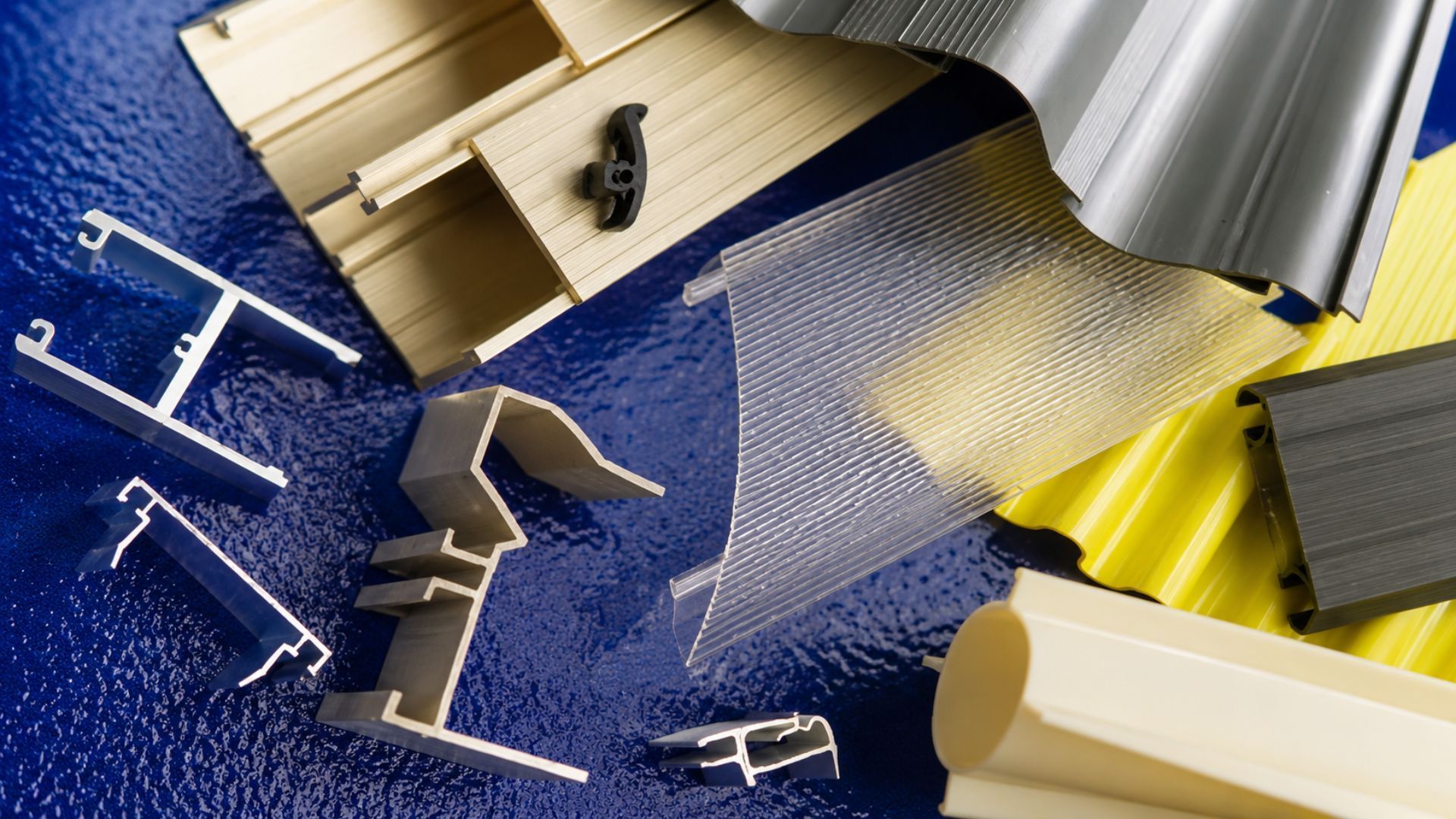 Assorted metal construction materials and tools on blue and yellow surfaces, viewed from above