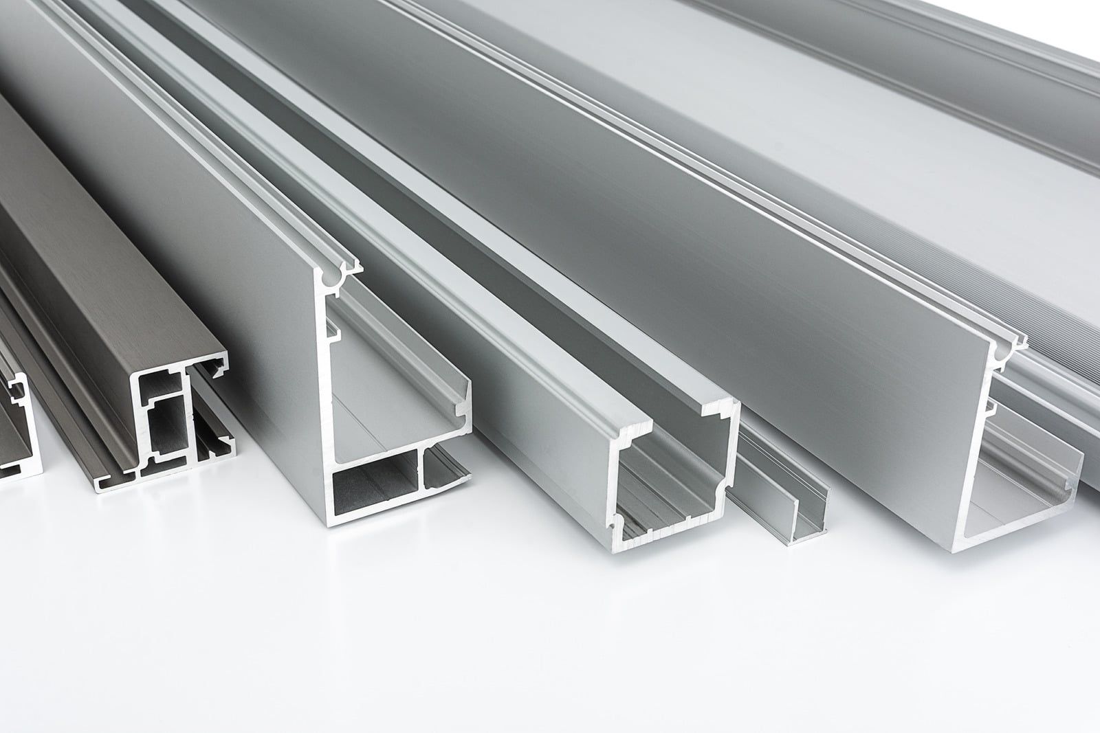 Stacked aluminum structural beams on snowy ground at a construction site