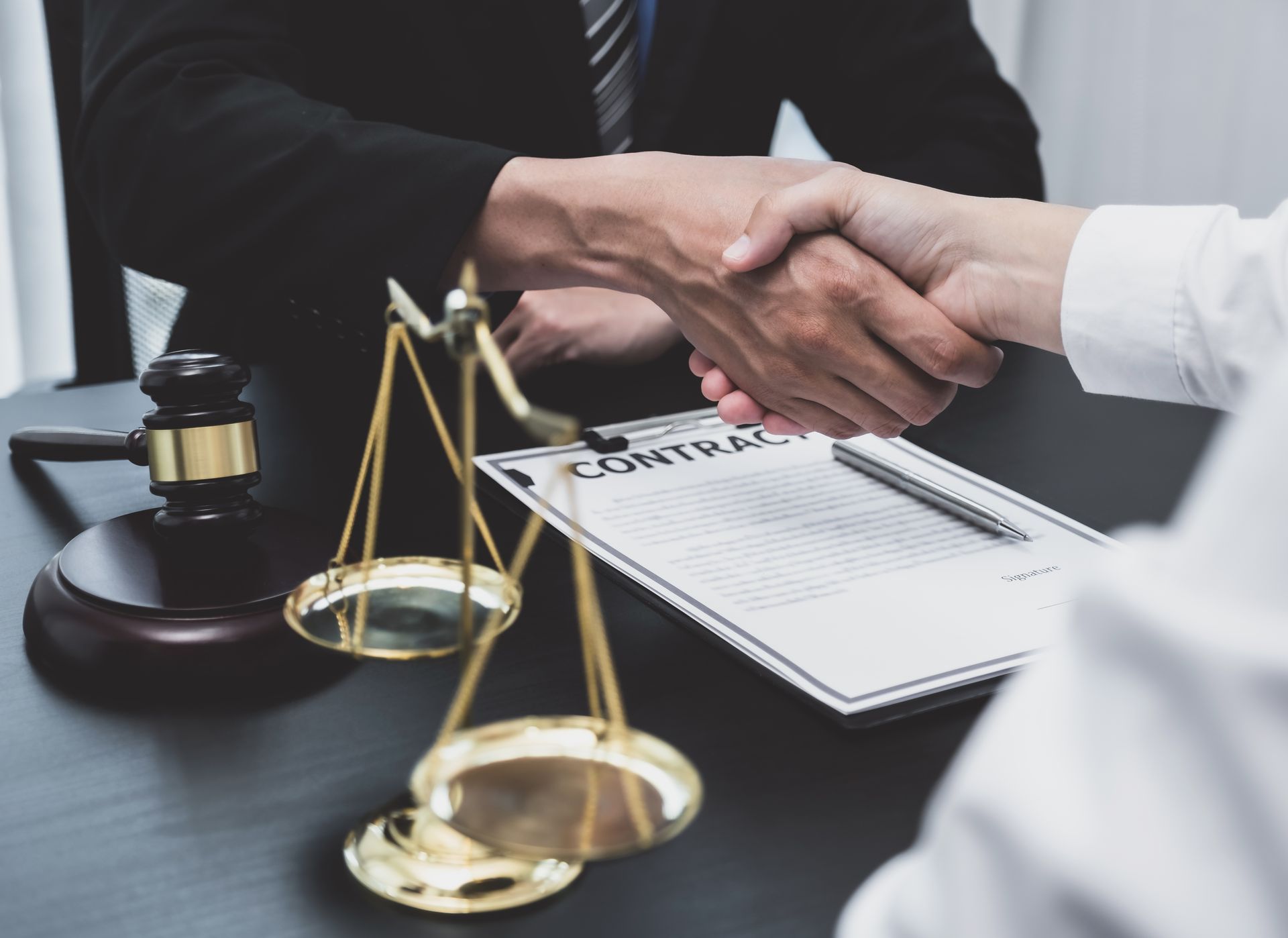 Lawyer shaking hands with a client beside a gavel.