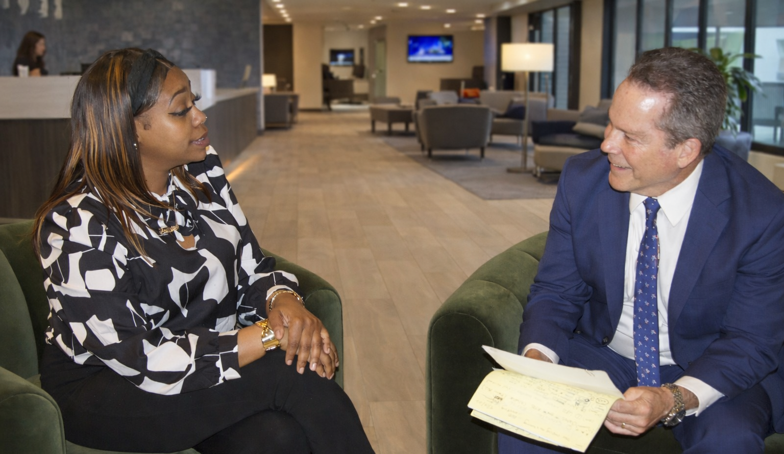 Two people shaking hands across a desk with a scale of justice.