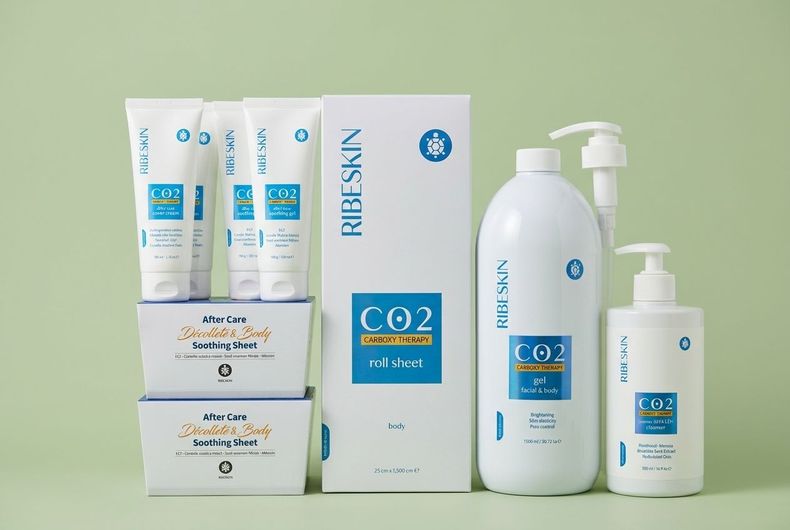 Vari prodotti e scatole per la cura della pelle di colore bianco su uno sfondo verde chiaro.