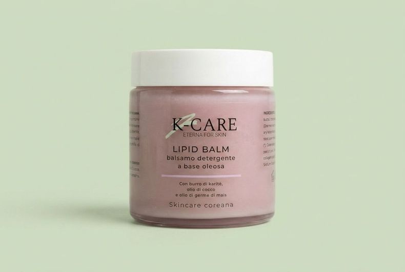 Vasetto di balsamo labbra K-CARE rosa con coperchio bianco su sfondo verde chiaro.